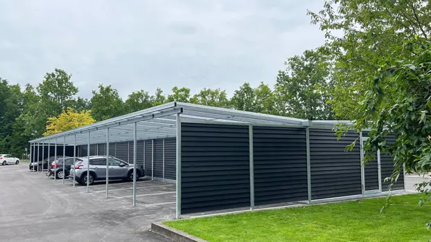 Große PLAN-Carportanlage. EasyPlank-Verkleidung. Solarzellen auf Teilen des Daches