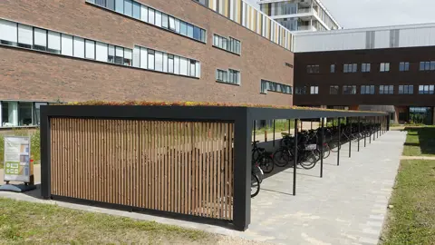 Große KUBIC-Fahrradüberdachung mit Sedum auf dem Dach und vertikalen Holzlamellen