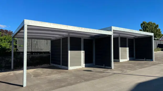 UNA-Carport mit integriertem Geräteschuppen in hügeligem Gelände