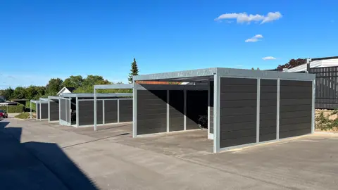 UNA-Carports mit zugehörigem Geräteschuppen in sehr hügeligem Gelände